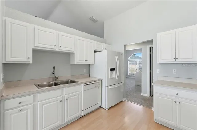 a kitchen with white cabinets and refrigerator