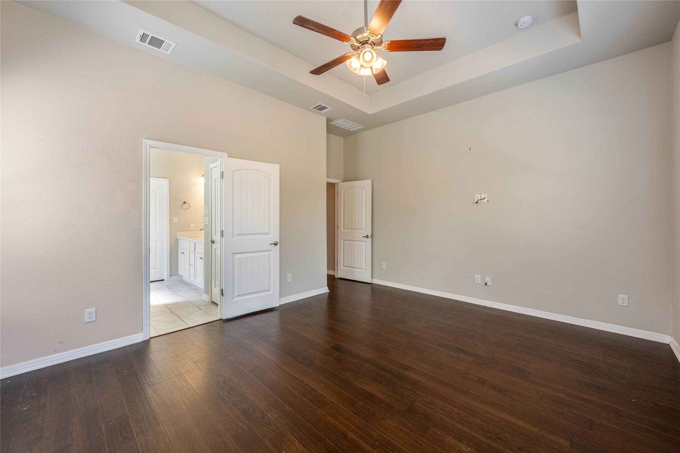 126 Rains Kyle, TX 78640 - Photo 12 of 22 Rich wood floors and a tray ceiling define this open, light-filled bedroom suite.