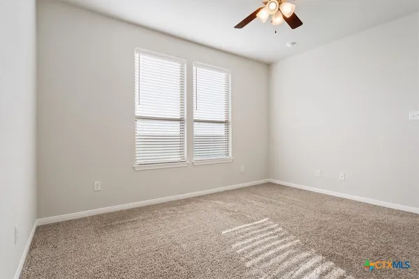 an empty room with a window and a ceiling fan