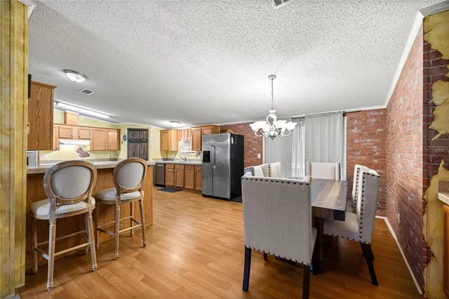 a living room with couches a dining table and a chandelier with wooden floor
