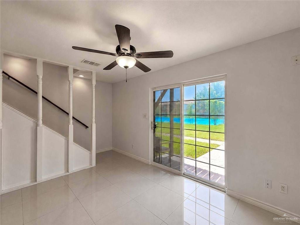 2201 South Jackson Road, Unit 2I Pharr, TX 78577 - Photo 8 of 23 Spacious interior featuring a contemporary ceiling fan, large sliding glass doors, white tile flooring, and a staircase with dark wood handrails and decorative balusters