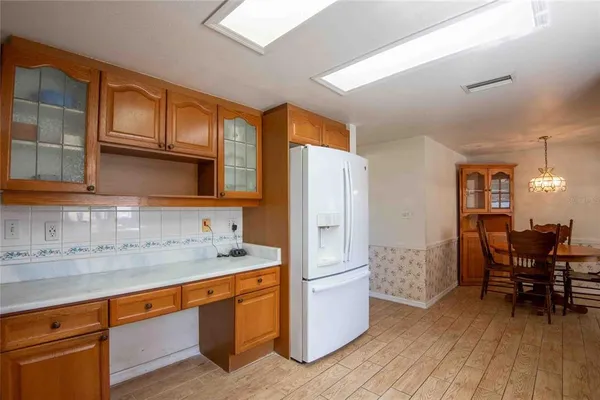 a kitchen with stainless steel appliances granite countertop a refrigerator a sink dishwasher a dining table and chairs with wooden floor