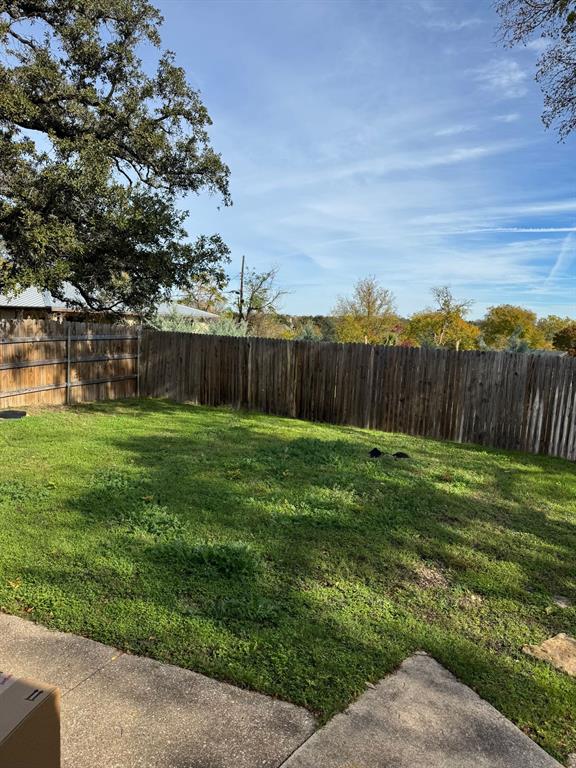 9551 Lechner Road, Unit G Fort Worth, TX 76179 - Photo 3 of 15 Fenced backyard with mature tree canopy, concrete patio, and a distant tree line