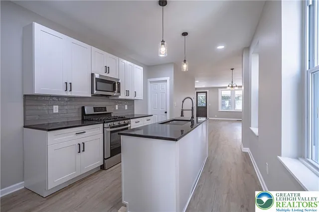 a large kitchen with stainless steel appliances kitchen island granite countertop a sink and a stove top oven