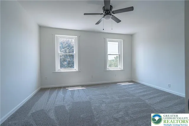 an empty room with windows and fan