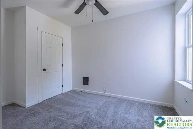an empty room with a ceiling fan and carpet