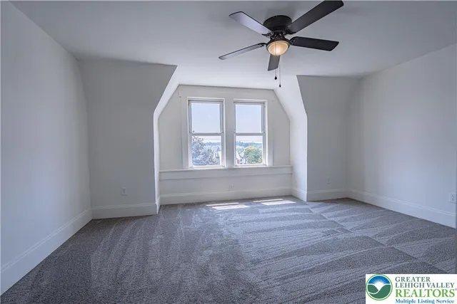 an empty room with windows and fan