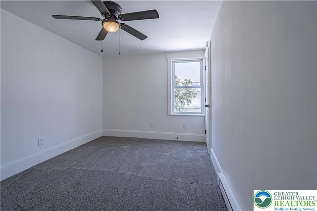 an empty room with windows and fan