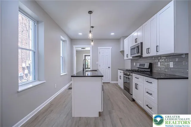 a large kitchen with stainless steel appliances granite countertop a stove a sink and white cabinets