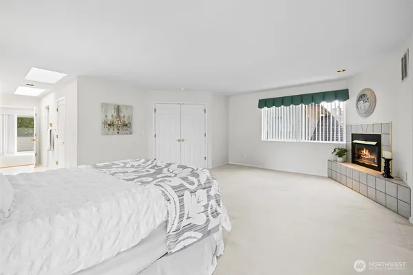 a spacious bedroom with a bed a fireplace and a window