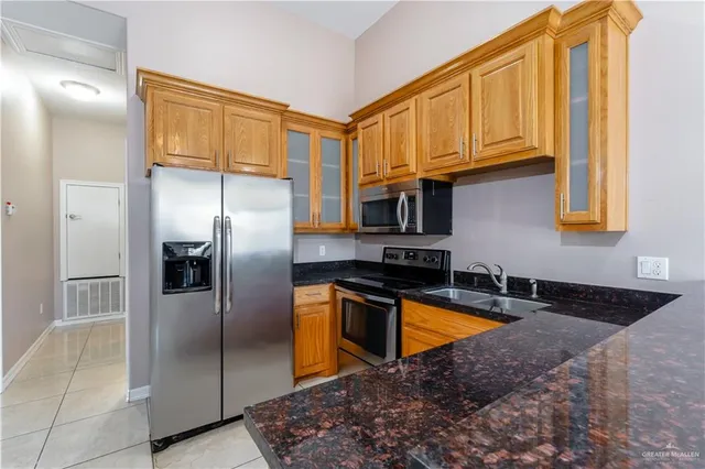 a kitchen with stainless steel appliances granite countertop a refrigerator a stove and a sink with granite countertops