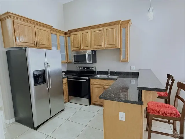 a kitchen with granite countertop a refrigerator stove and microwave