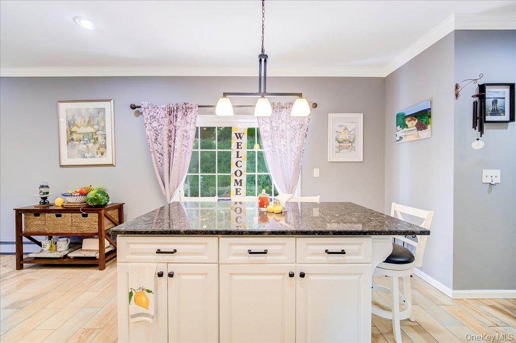 104 Wiccopee Road Putnam Valley, NY 10579 - Photo 16 of 50 Kitchen island featuring a dark speckled countertop, white cabinetry with black hardware, and an integrated breakfast bar