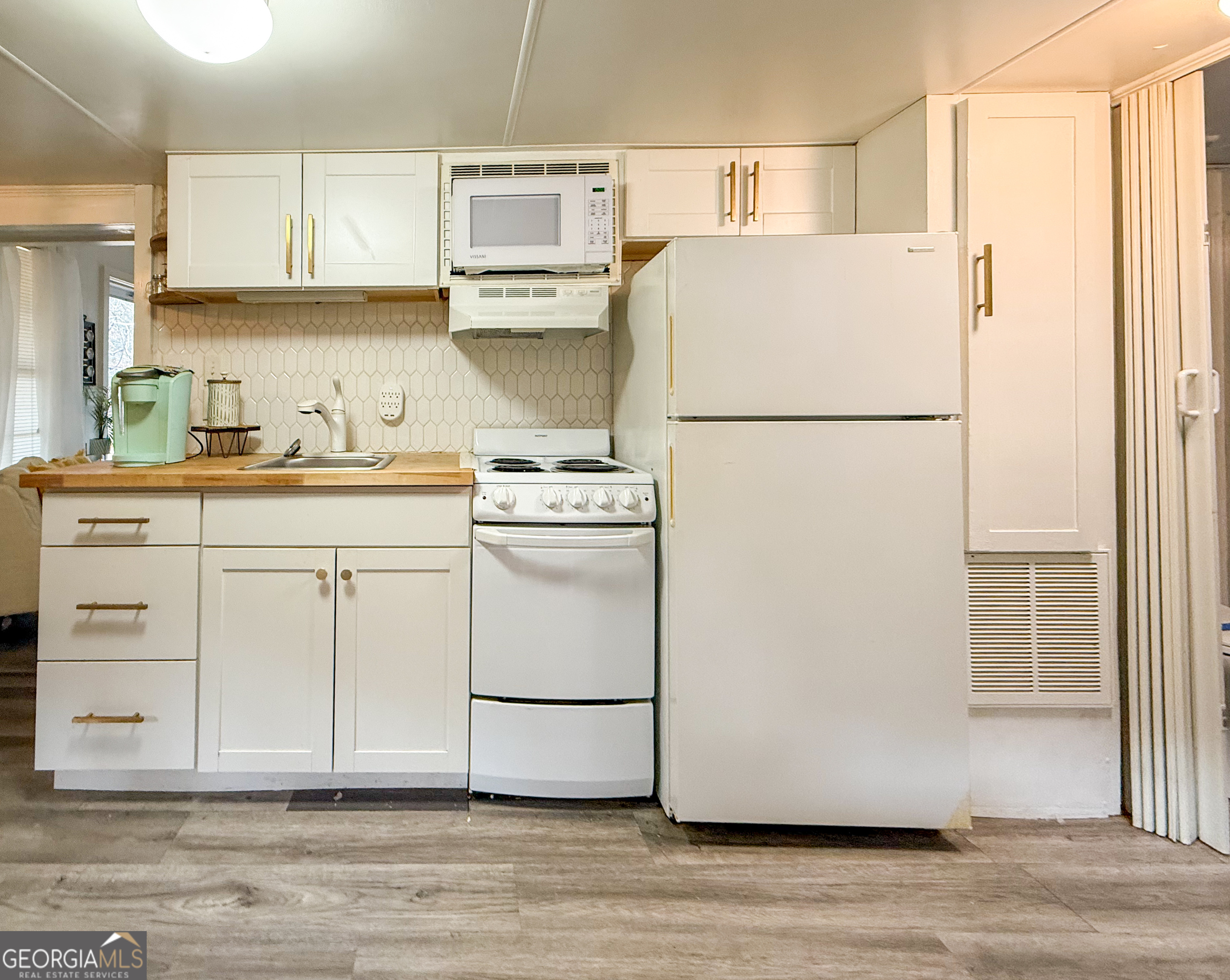 227 Canyon Pass Cleveland, GA 30528 - Photo 10 of 15 a kitchen with a refrigerator a stove a sink and white cabinets with wooden floor