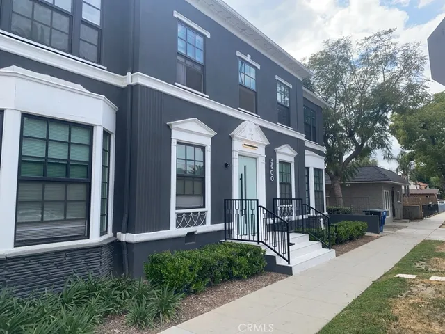 a view of a brick house with many windows and plants