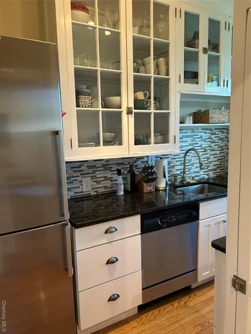 a kitchen with granite countertop white cabinets and stainless steel appliances