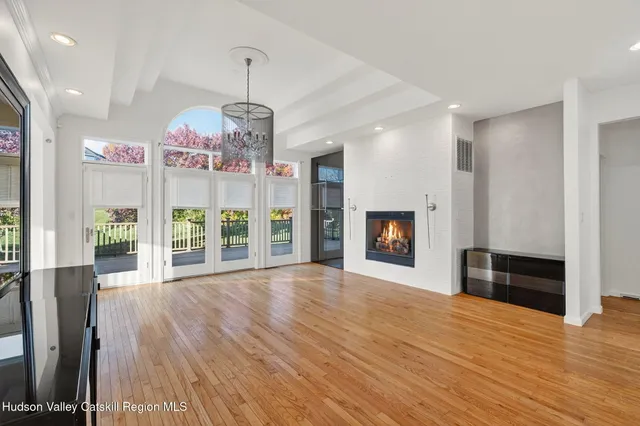 an empty room with wooden floor fireplace and windows