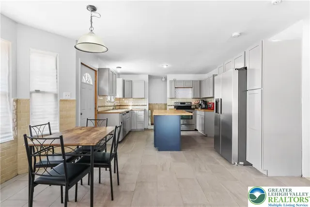 a kitchen with stainless steel appliances kitchen island granite countertop a table chairs sink and cabinets