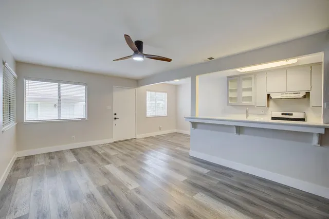 a view of an empty room with a window and wooden floor