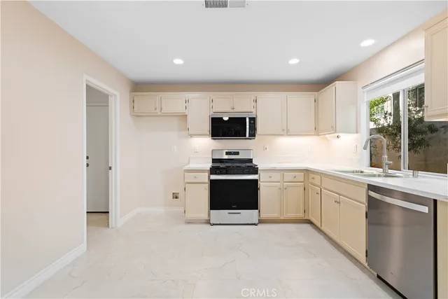 a kitchen with granite countertop white cabinets and stainless steel appliances