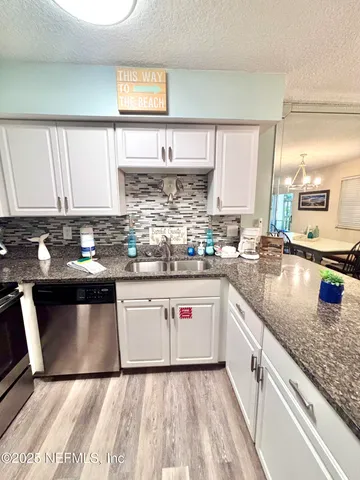 a kitchen with stainless steel appliances granite countertop a refrigerator a stove a sink a dining table and chairs