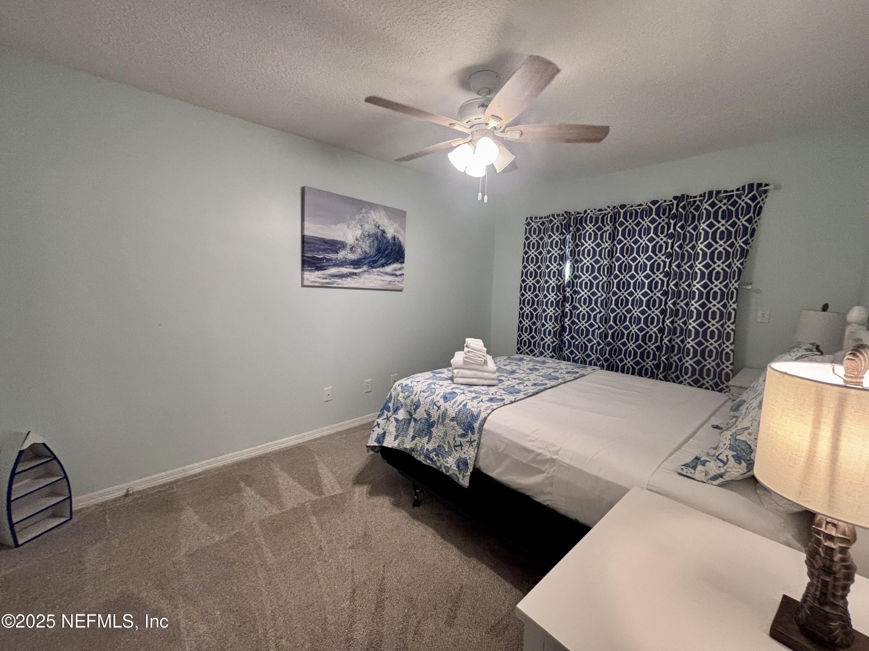 3165 1st Avenue, Unit 13 Fernandina Beach, FL 32034 - Photo 21 of 37 a bedroom with a bed and a chandelier