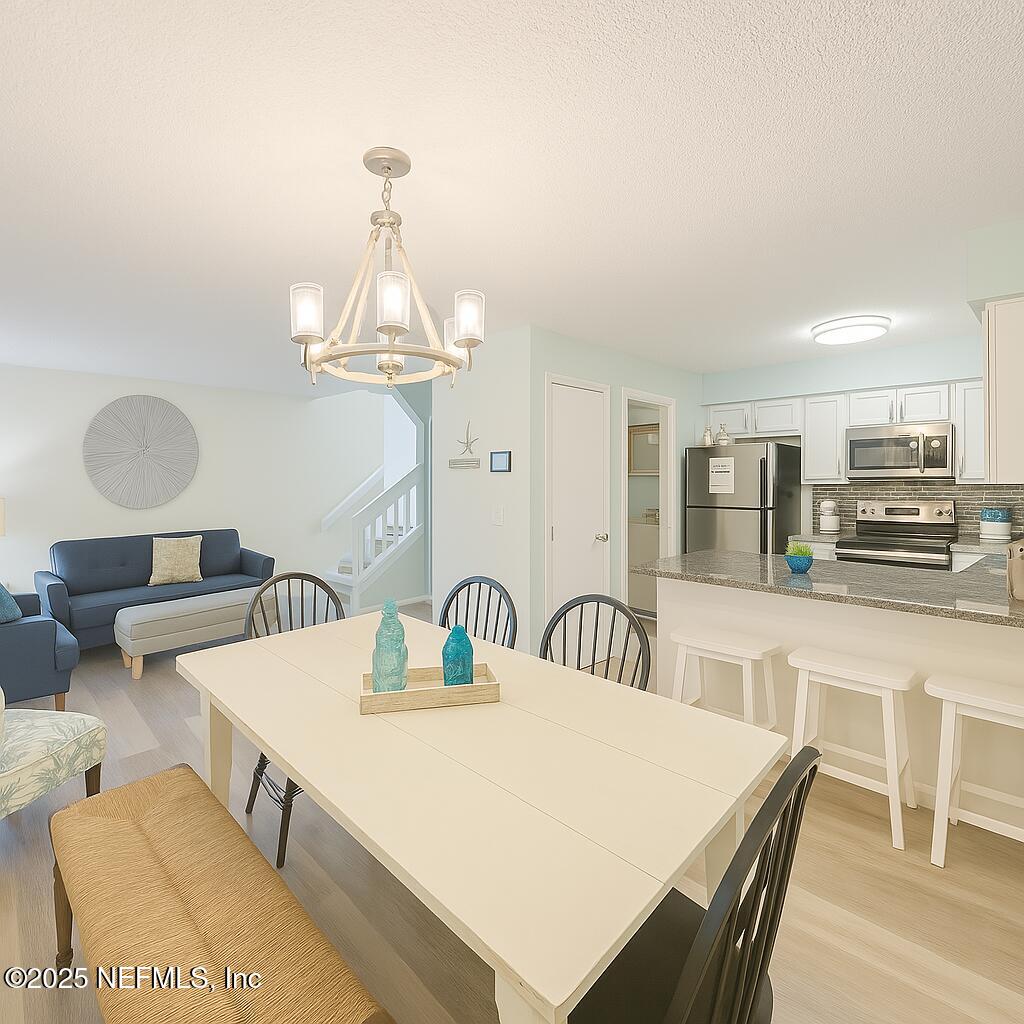 3165 1st Avenue, Unit 13 Fernandina Beach, FL 32034 - Photo 10 of 37 a dining room with wooden floor a chandelier a wooden table and chairs