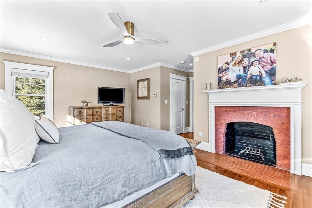 21 Sheffield West Winchester, MA 01890 - Photo 23 of 40 a spacious bedroom with a large bed a fireplace and a chandelier