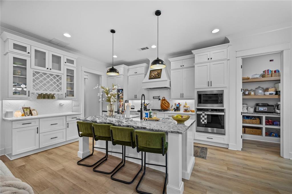 1159 Locklin Road Monroe, GA 30655 - Photo 3 of 63 a kitchen with stainless steel appliances granite countertop a stove top oven a sink a dining table and chairs with wooden floor