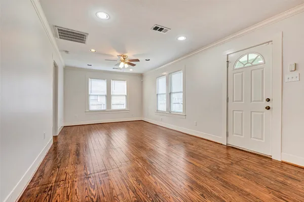 an empty room with wooden floor and windows