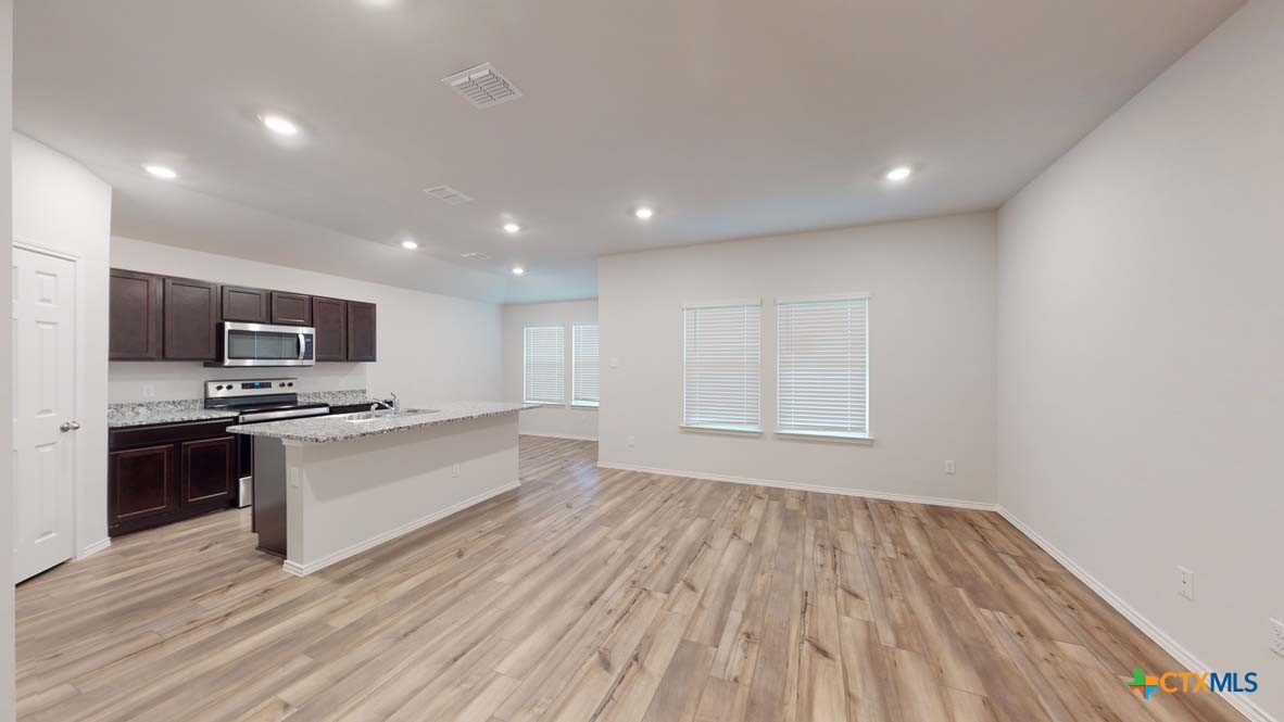 553 Hector Loop Georgetown, TX 78626 - Photo 3 of 21 a large kitchen with stainless steel appliances a large counter top a stove a microwave and a refrigerator