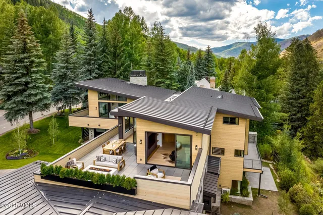 a kitchen with stainless steel appliances granite countertop a stove a sink a refrigerator a dining table and chairs with wooden floor