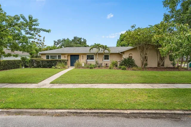 a view of house in front of a big yard with large trees