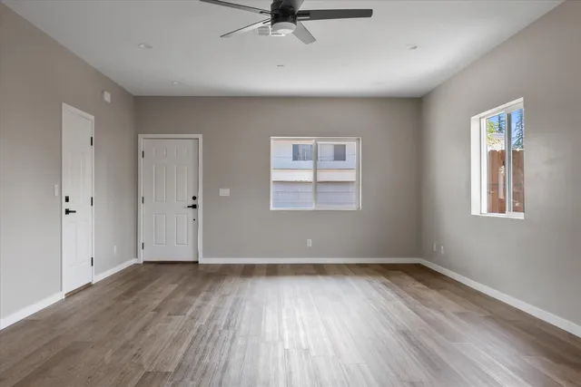 a view of an empty room with wooden floor and a window
