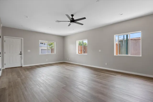 a view of an empty room with wooden floor and a window