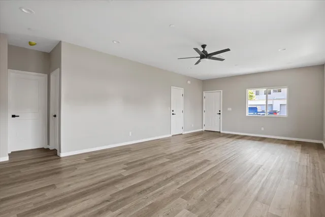 an empty room with wooden floor ceiling fan and windows
