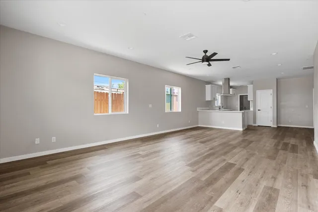 a view of an empty room with a window and wooden floor