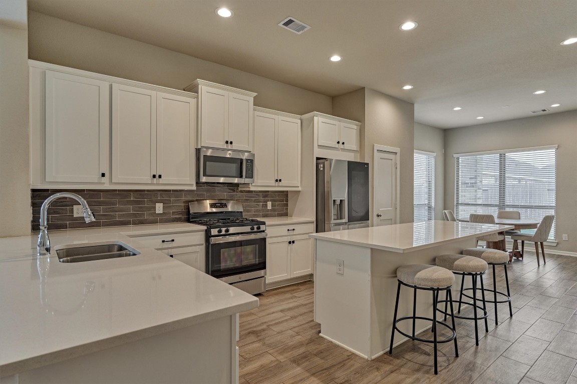10545 Wild Chives Conroe, TX 77385 - Photo 2 of 34 a large kitchen with stainless steel appliances granite countertop a stove a sink a refrigerator and white cabinets