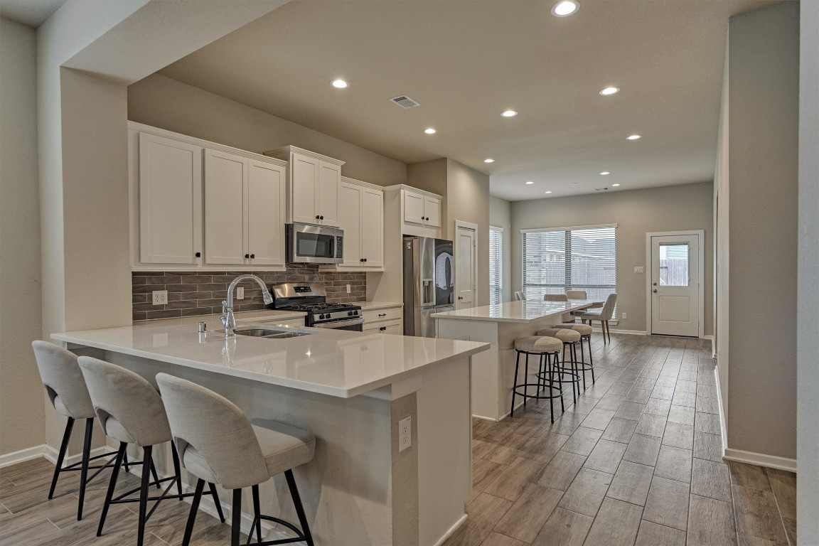10545 Wild Chives Conroe, TX 77385 - Photo 6 of 34 a kitchen with stainless steel appliances granite countertop a table chairs sink refrigerator and cabinets
