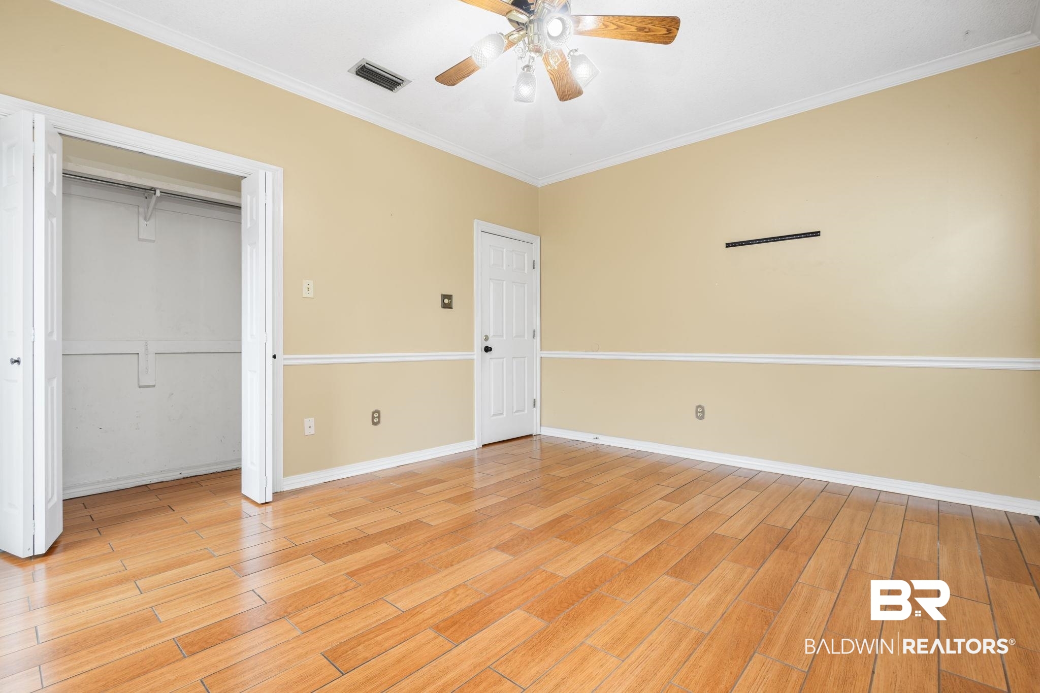 7540 2 Mile Road Irvington, AL 36544 - Photo 49 of 82 Spacious room featuring wood-finish flooring, two-tone painted walls with chair rail molding, and a ceiling fan with integrated lighting