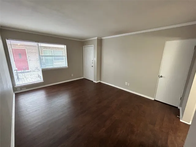 an empty room with wooden floor and windows with curtains