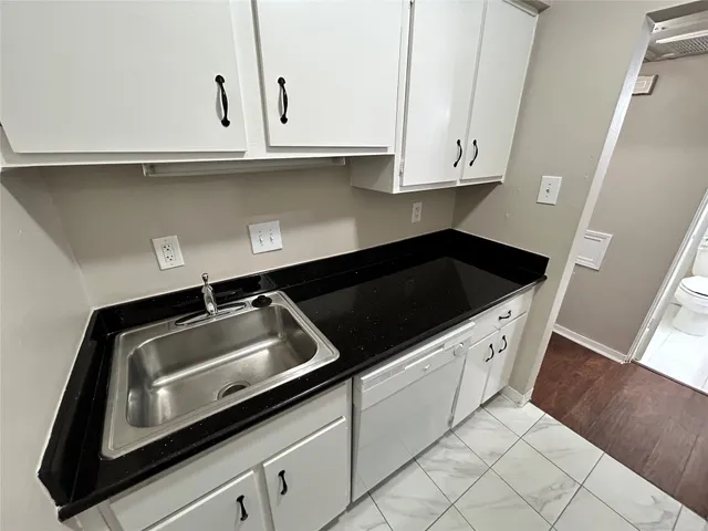 a kitchen with granite countertop white cabinets and a sink