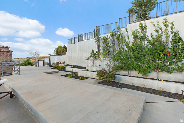 912 North Loafer Canyon Road Elk Ridge, UT 84651 - Photo 54 of 98 Multi-level concrete patio with integrated planters, mature greenery, and tiered retaining walls featuring black metal railings