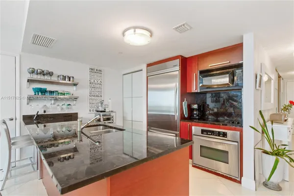a kitchen with stainless steel appliances kitchen island granite countertop a refrigerator and a stove top oven