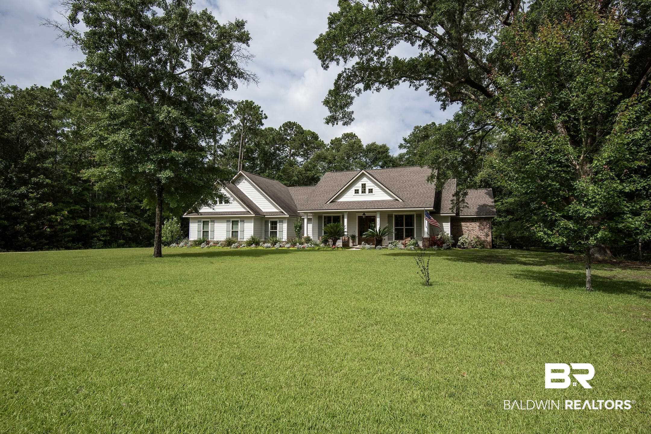 18754 Treasure Oaks Road Gulf Shores, AL 36542 - Photo 3 of 53 Expansive green lawn presenting a traditional-style residence with white siding, a covered front porch, and dormer windows