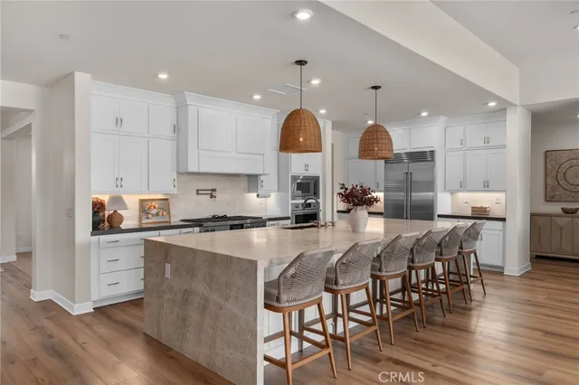 a kitchen with stainless steel appliances granite countertop a stove a sink dishwasher a dining table and chairs with wooden floor