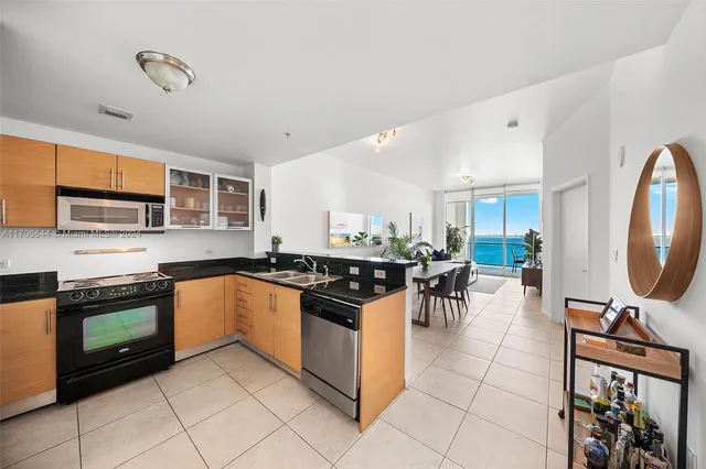 a kitchen with stainless steel appliances granite countertop a stove top oven a sink a dining table and chairs