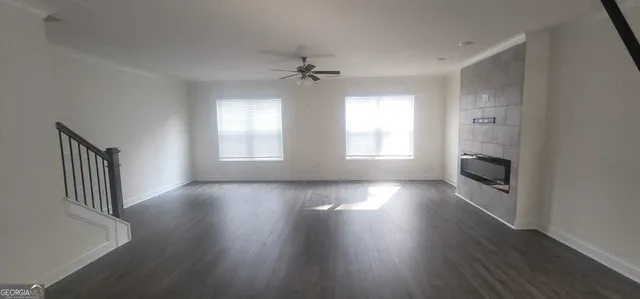 an empty room with wooden floor fireplace and windows