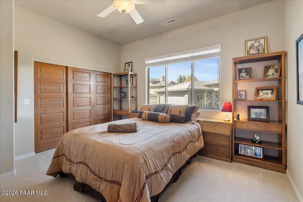 a bedroom with a bed table and a large window