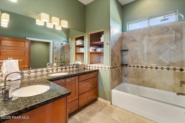 a bathroom with a granite countertop tub sink and mirror